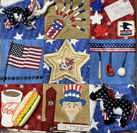 This photo is a close up of a fidget quilt showing nine squares of the quilt, each with a patriotic theme.